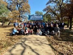 Large group photo of all participants gathered under the finish line/banner