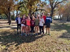 Small group of runners posing together on the course with fall foliage in background